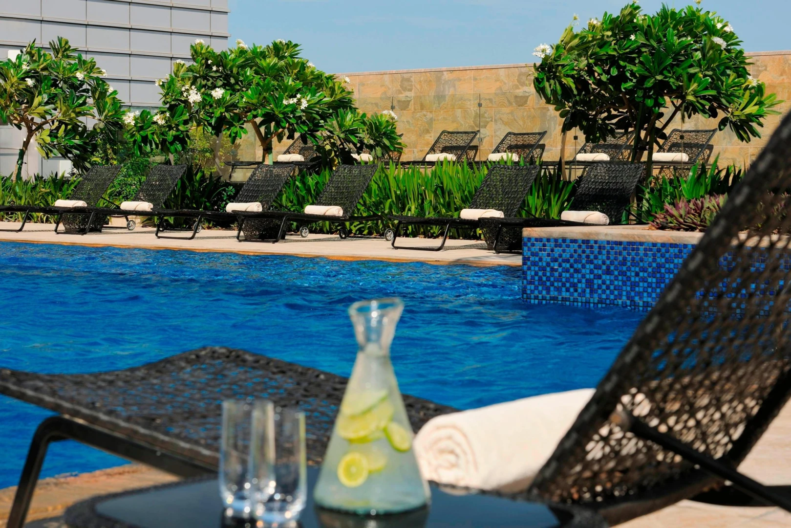 JW Marriott Marquis Dubai poolside with loungers and tropical plants.