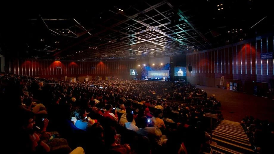 Crowded event at Dubai World Trade Centre auditorium, dimly lit atmosphere.
