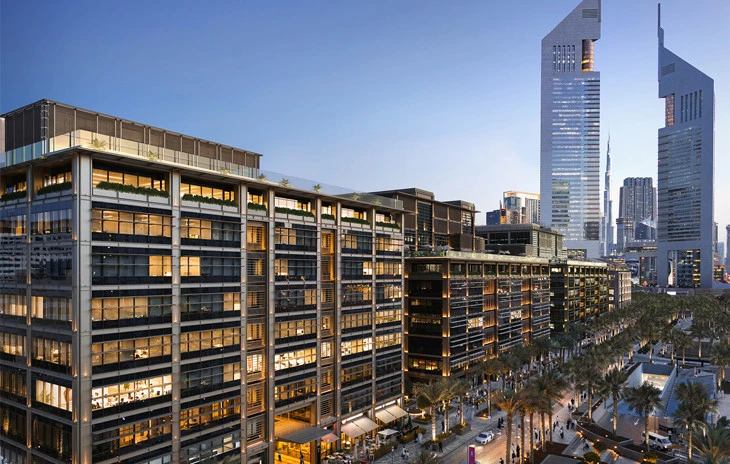 Dubai World Trade Centre with skyscrapers and palm-lined street at dusk.