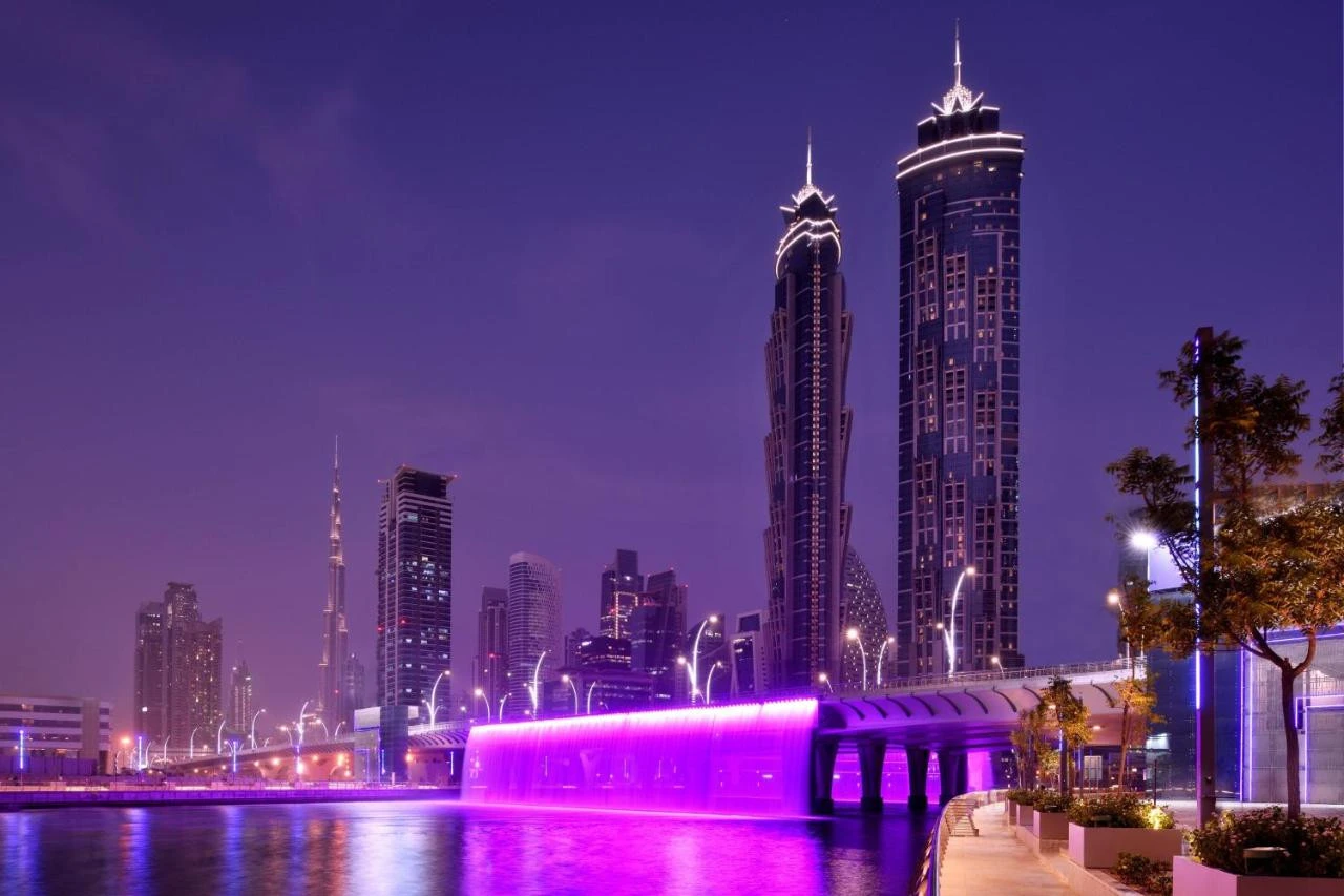 JW Marriott Marquis Hotel Dubai illuminated at night with purple lights.