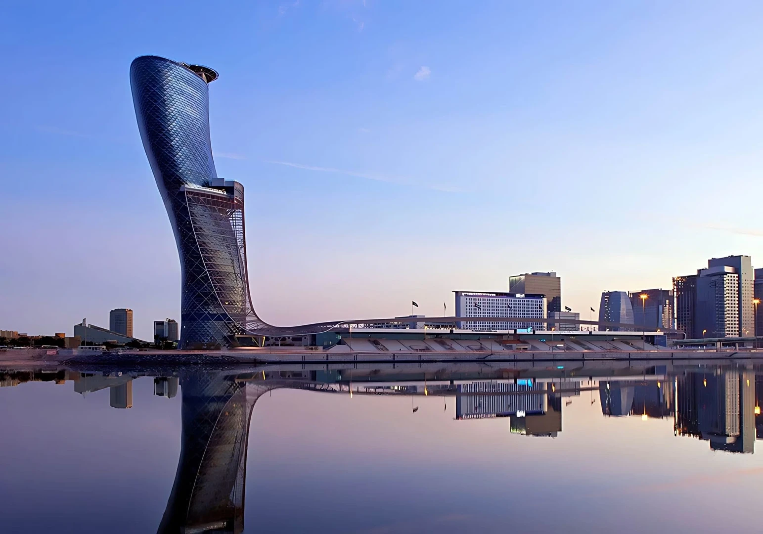 Capital Gate tower at ADNEC Centre, Abu Dhabi, reflecting in water.