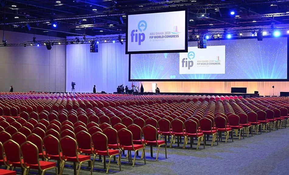Empty conference hall at ADNEC Centre Abu Dhabi with red chairs.