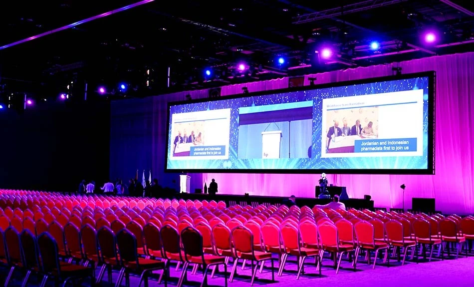 ADNEC Centre Abu Dhabi hall with red seating and large screens.