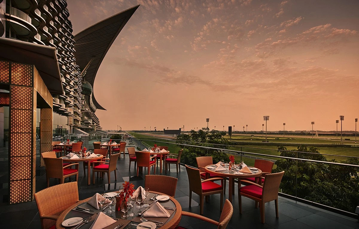 Outdoor dining at The Meydan Hotel terrace, Dubai, during sunset.