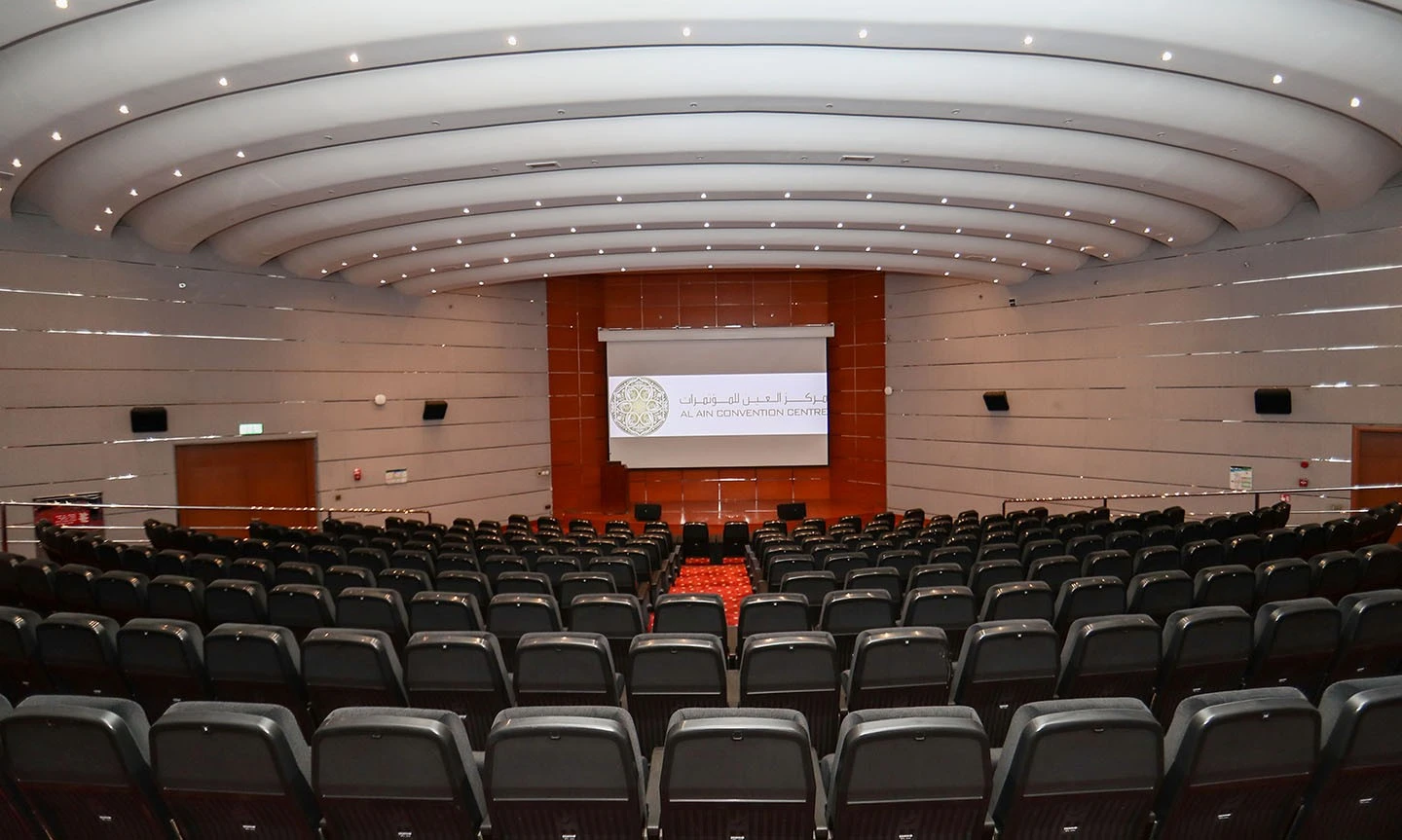 ADNEC Centre Al Ain auditorium with rows of empty seats.