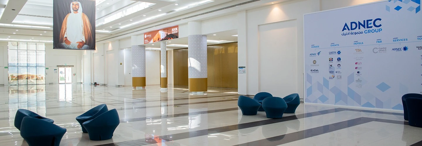 Spacious ADNEC Centre Al Ain lobby with seating and large portrait.