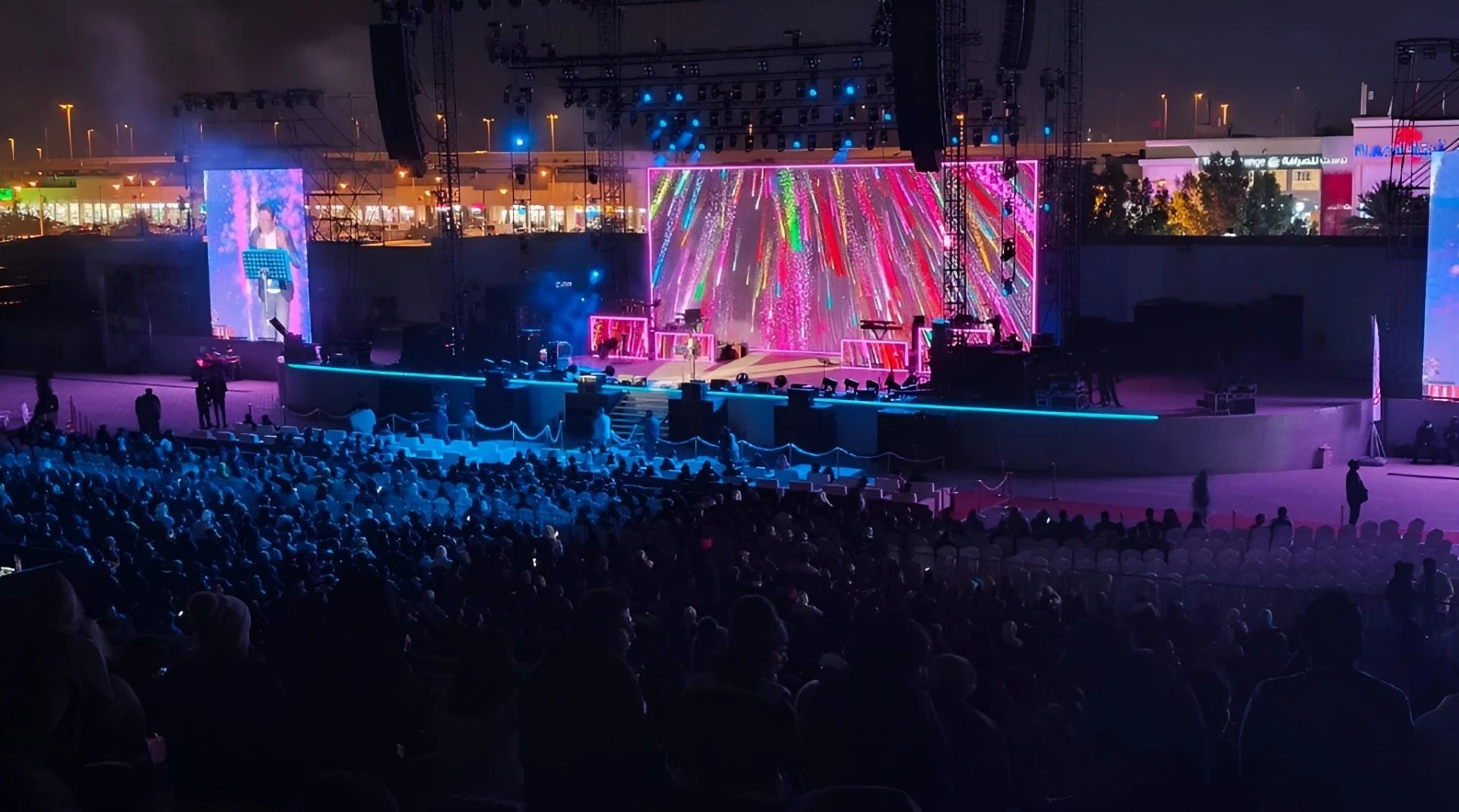 Colorful concert at Asian Town Amphitheater, Doha, with vibrant stage lights.